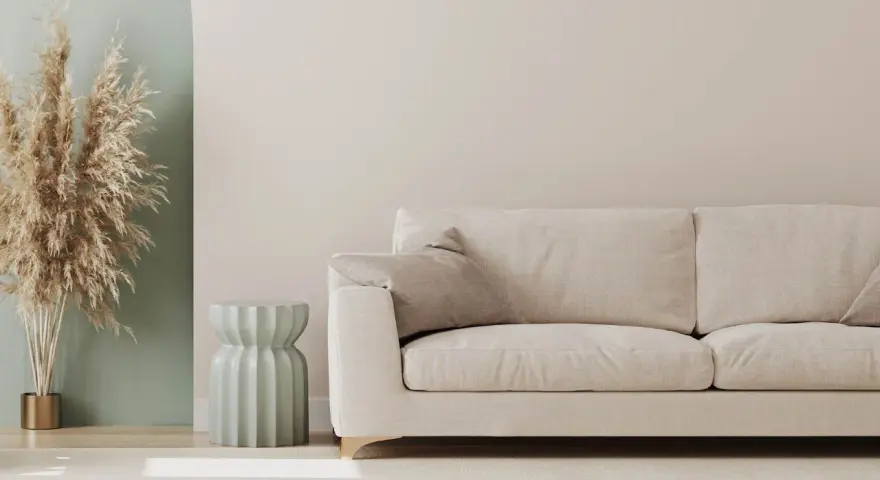 Jasna sofa i dekoracje z traw pampasowych to świetny pomysł na pustą ścianę w salonie.