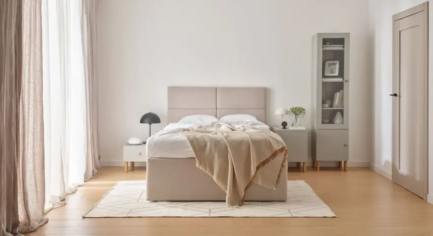 Beżowa sypialnia inspiracje: przytulne łóżko z narzutą, jasne zasłony i minimalistyczne meble tworzą spokojną atmosferę.