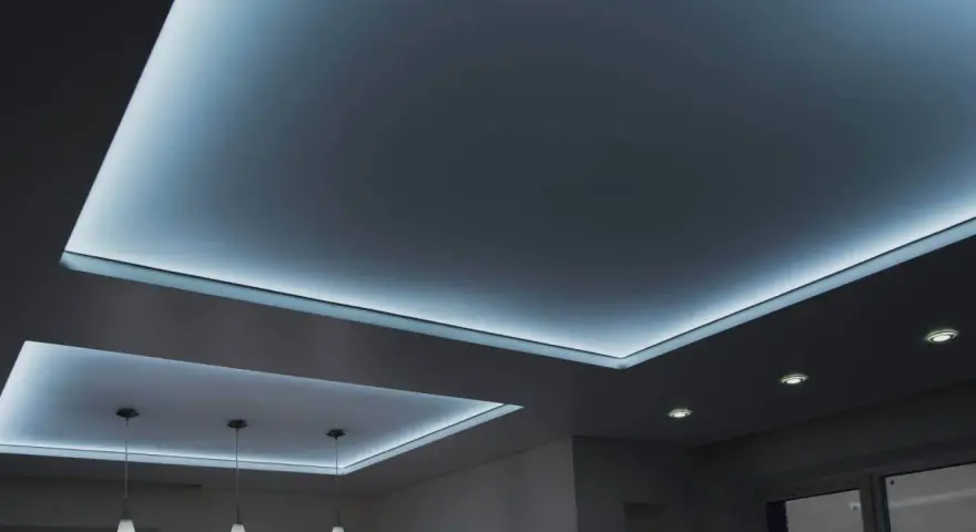 Nowoczesny sufit napinany w salonie z subtelnym, niebieskim podświetleniem LED tworzy relaksującą atmosferę.