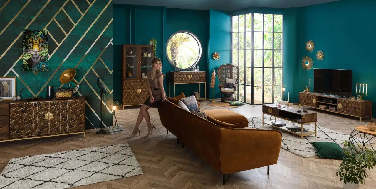 Elegancja w stylu art deco: salon z turkusowymi ścianami, złotymi akcentami, aksamitną kanapą i meblami z geometrycznymi wzorami.