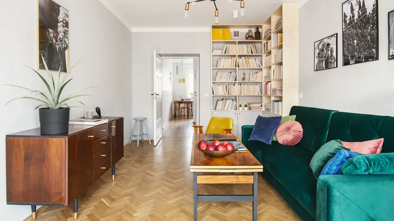 Kultowe meble PRL: drewniana komoda, zielona kanapa i żółty fotel tworzą przytulny salon.