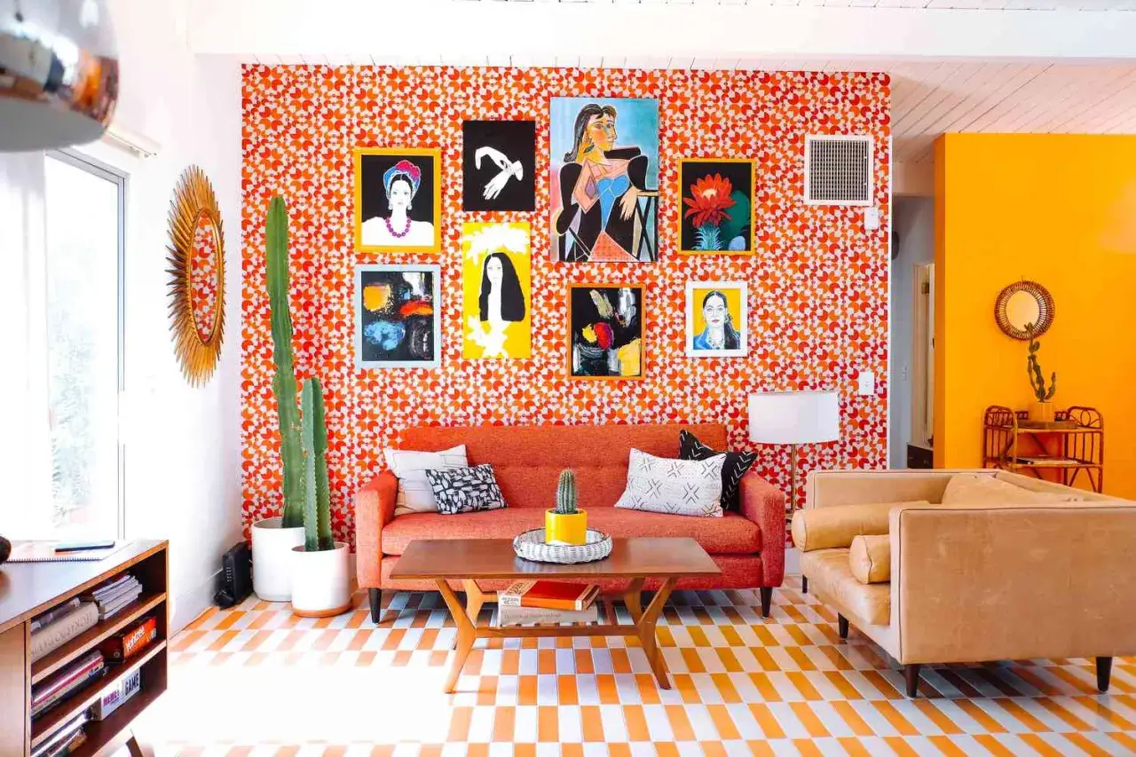 Salon w stylu retro inspiracje: pomarańczowa ściana z grafikami, kanapa, stolik i podłoga w geometryczne wzory.