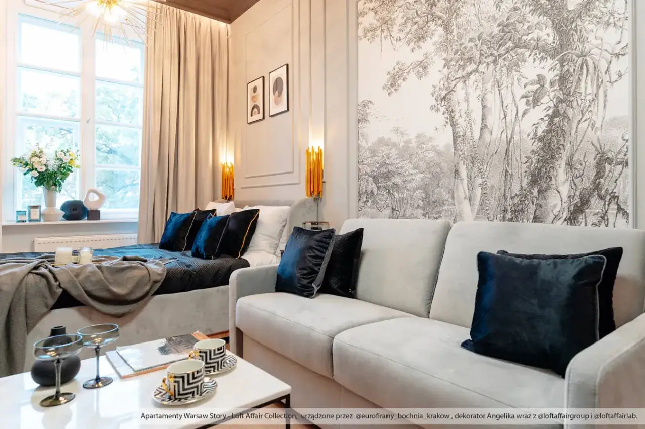 Elegancka sofa z aksamitnymi poduszkami, na jakiej wysokości półka nad kanapą? W tle łóżko i tapeta z motywem dżungli.