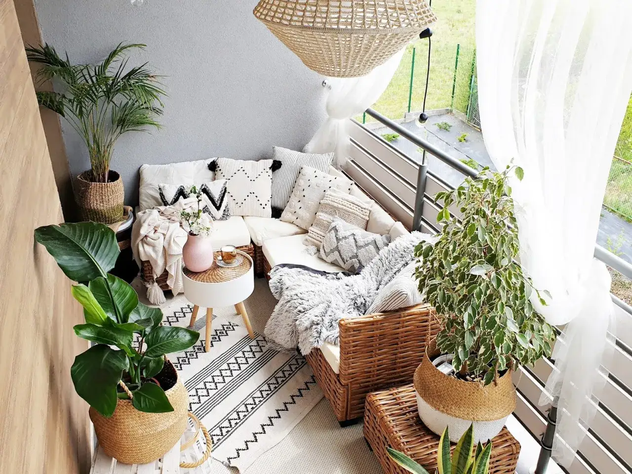 Przytulny balkon boho inspiracje: rattanowe meble, mnóstwo poduszek, rośliny i plecione kosze tworzą relaksującą oazę.