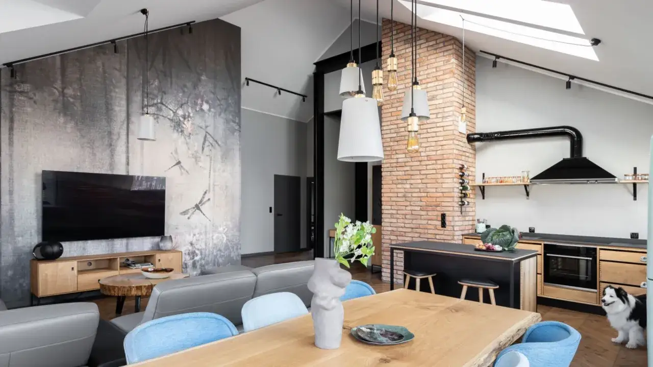 Salon loft inspiracje: szara sofa, drewniany stół, ceglana ściana i tapeta z ważkami tworzą przytulną przestrzeń.