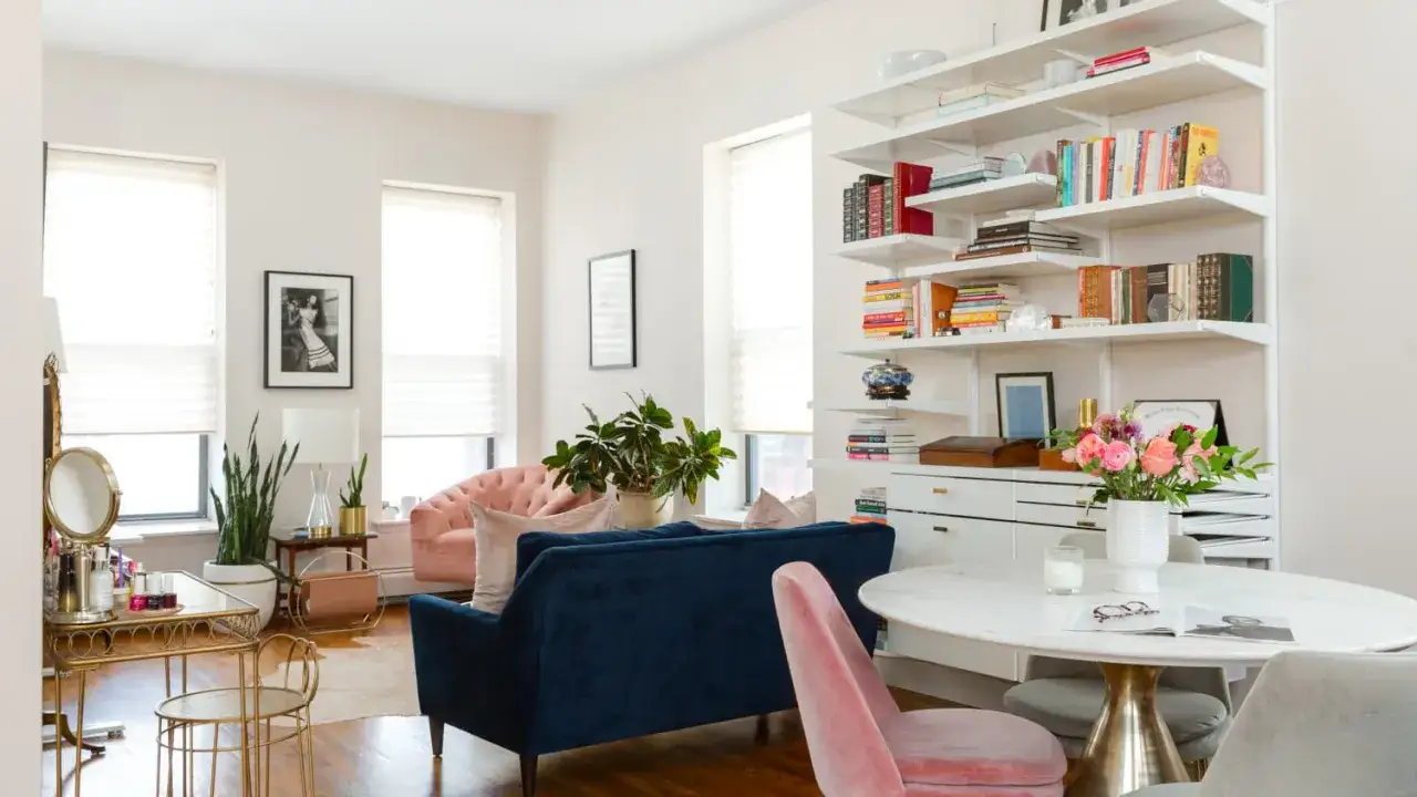 Przytulna domowa biblioteczka w małym mieszkaniu. Wygodne kanapy, stolik z kwiatami i regały pełne książek tworzą ciepłą atmosferę.