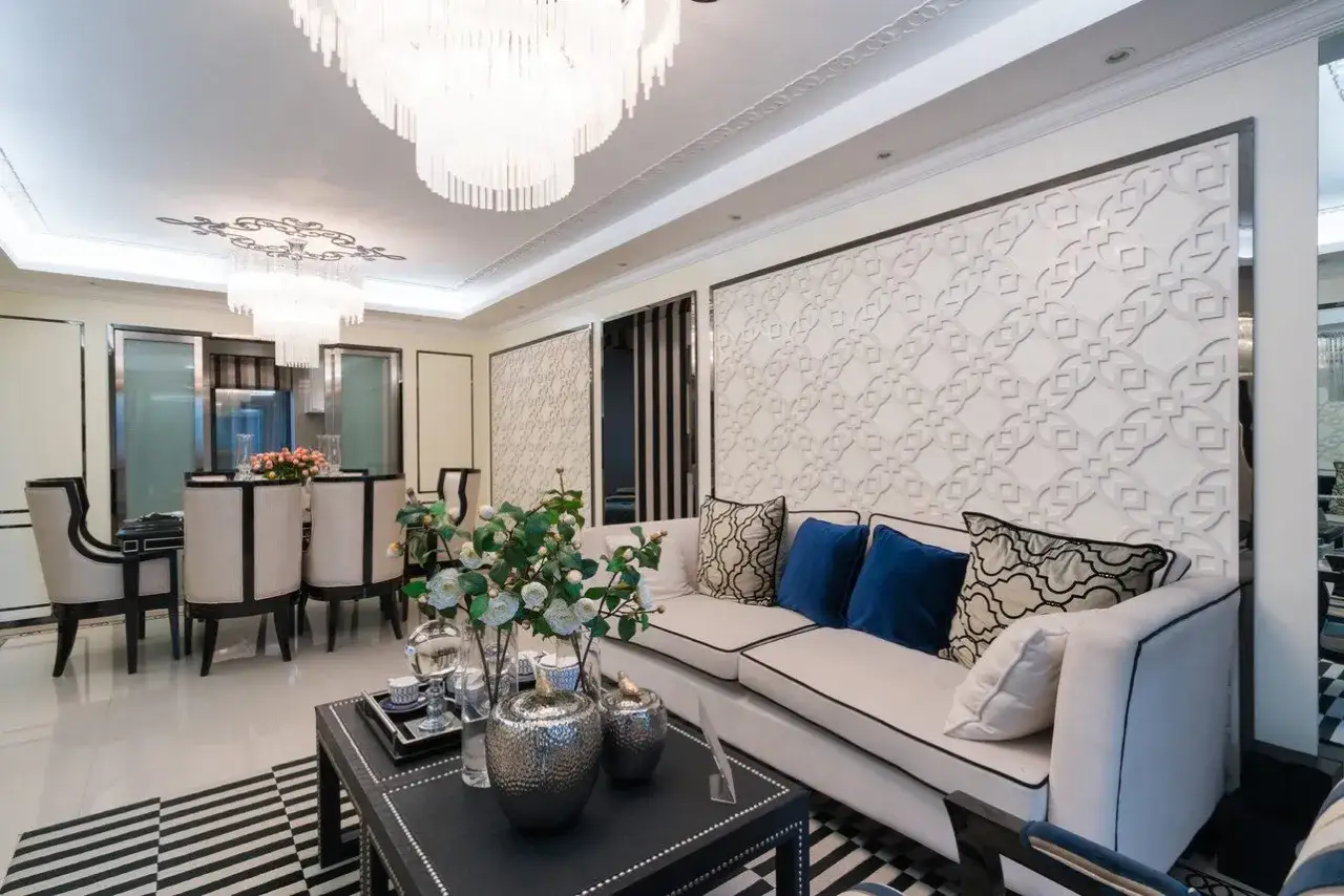 Elegancki salon w stylu nowojorskim z białymi kanapami, ozdobnymi panelami ściennymi i kryształowymi żyrandolami.