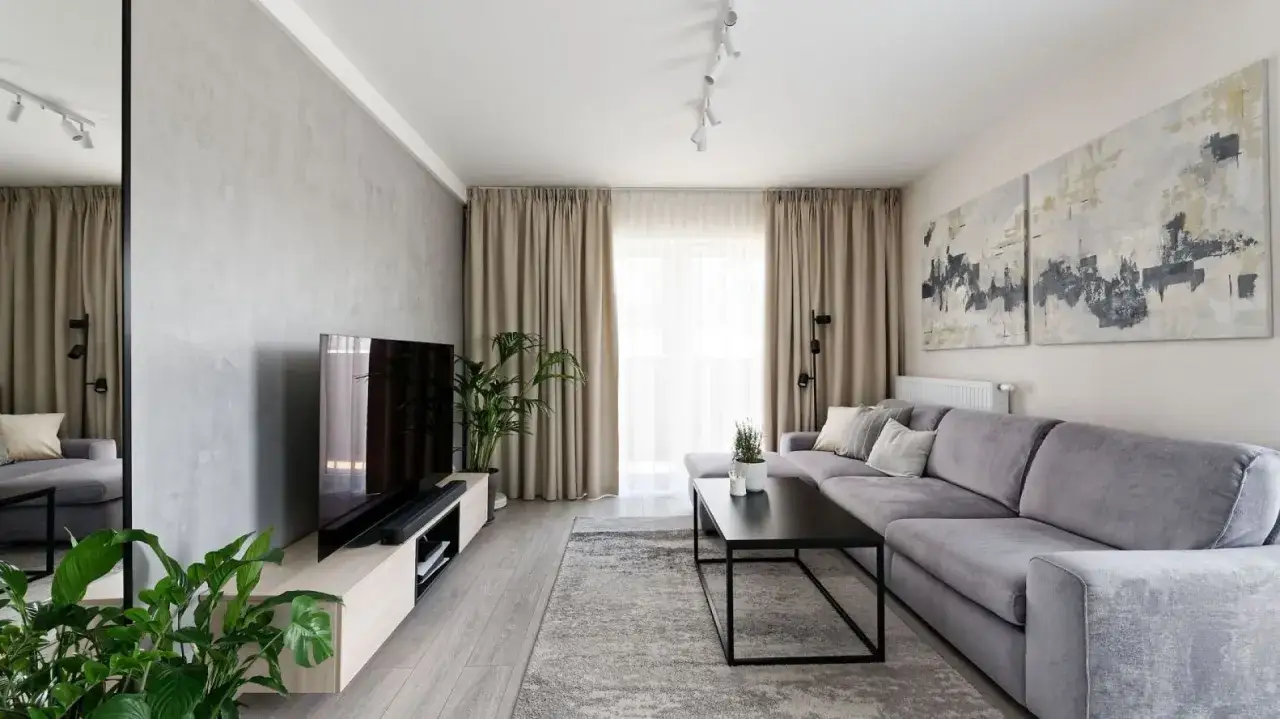 Nowoczesna ściana za kanapą w salonie z betonową fakturą, obok telewizora i roślin.