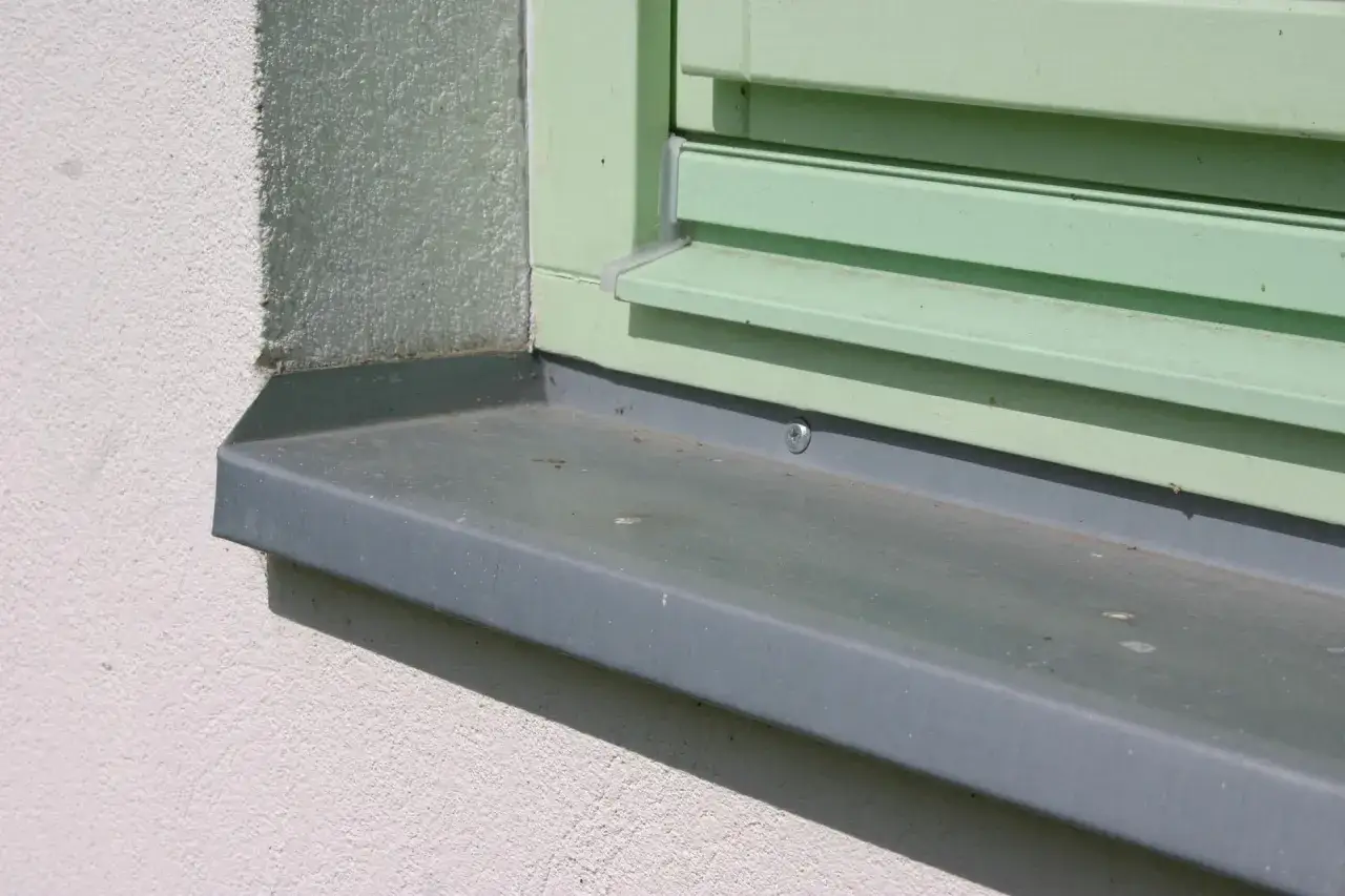 Szary parapet zewnętrzny wystaje ok. 5 cm od ściany, idealnie chroniąc okno.